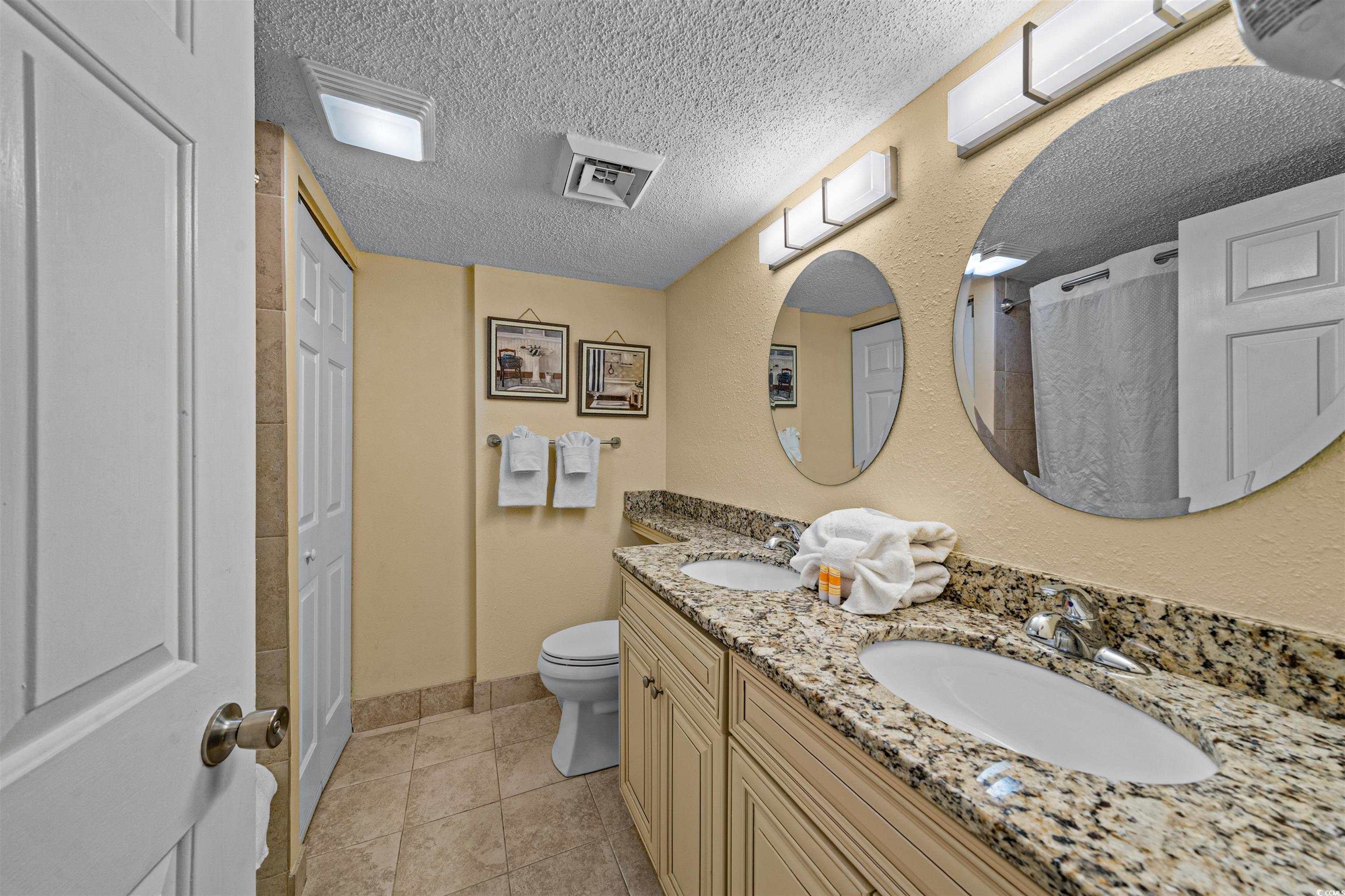 5308 North Ocean Boulevard, Unit 2006 Myrtle Beach, SC 29577 - Photo 19 of 37 Bathroom featuring a textured ceiling, a shower/tub combo with curtain, double vanity, and tile floors