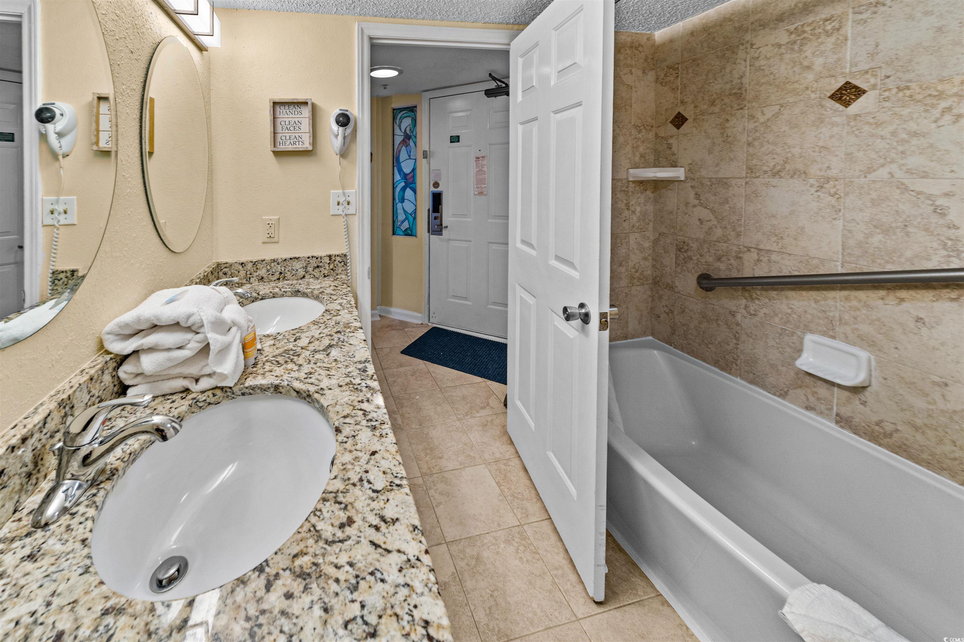 5308 North Ocean Boulevard, Unit 2006 Myrtle Beach, SC 29577 - Photo 20 of 37 Bathroom featuring a textured ceiling, a shower/tub combo with curtain, double vanity, and tile floors