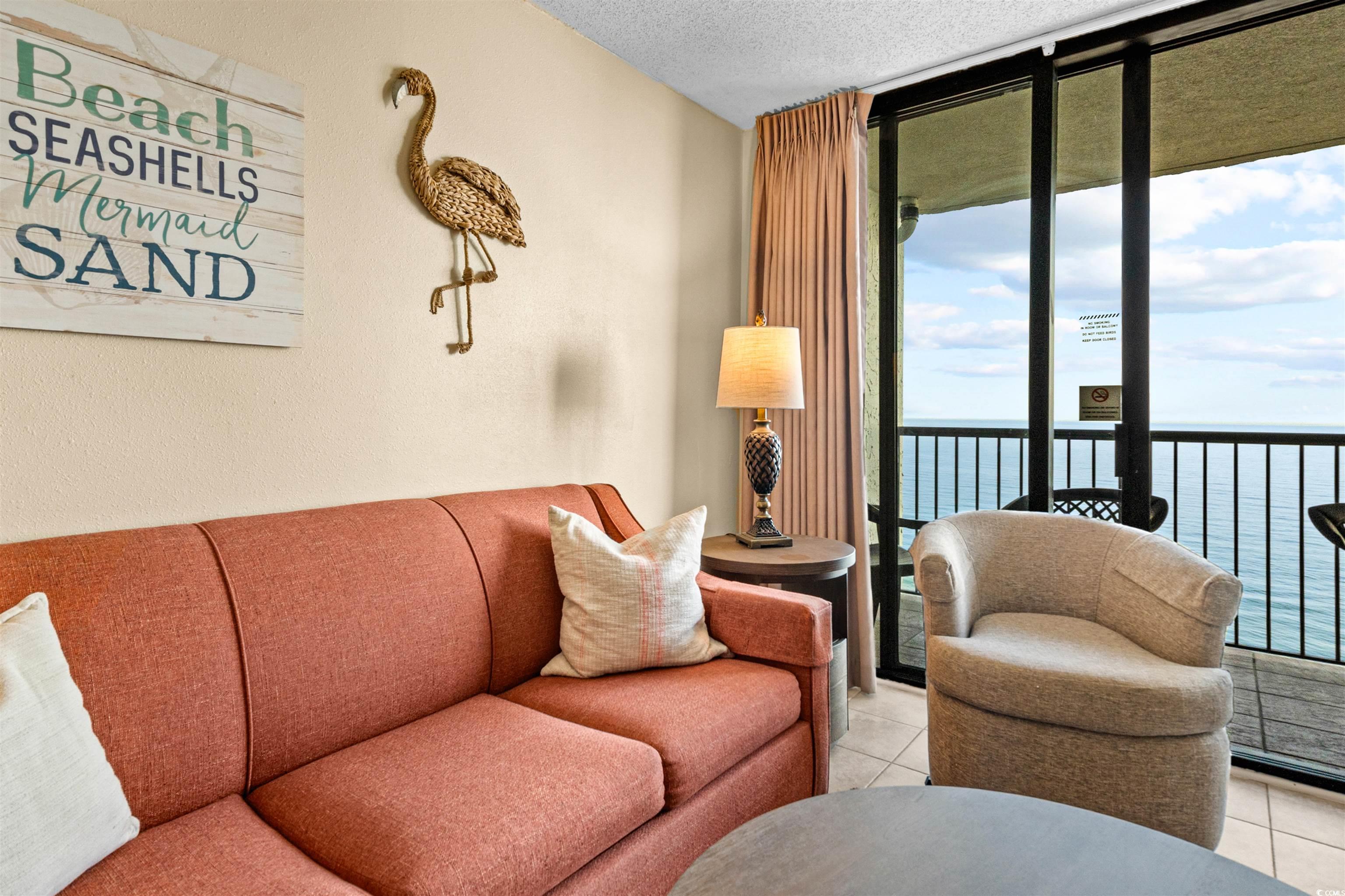 5308 North Ocean Boulevard, Unit 2006 Myrtle Beach, SC 29577 - Photo 8 of 37 Living area with oceanfront view, floor to ceiling glass slider, textured ceiling, and tile floors