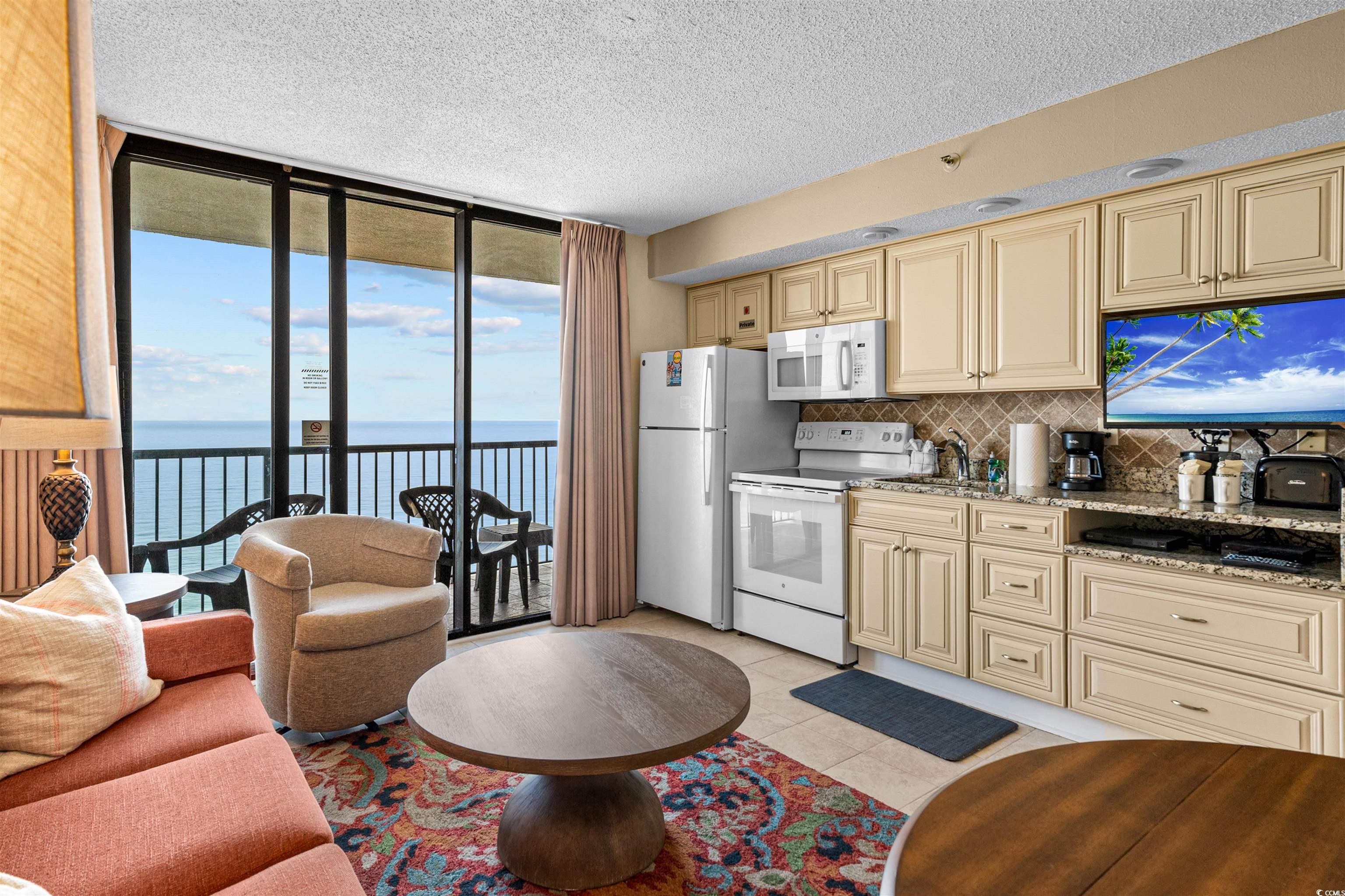 5308 North Ocean Boulevard, Unit 2006 Myrtle Beach, SC 29577 - Photo 9 of 37 Kitchen with floor to ceiling glass slider, cream cabinets, oceanfront view, white appliances, and granite countertops