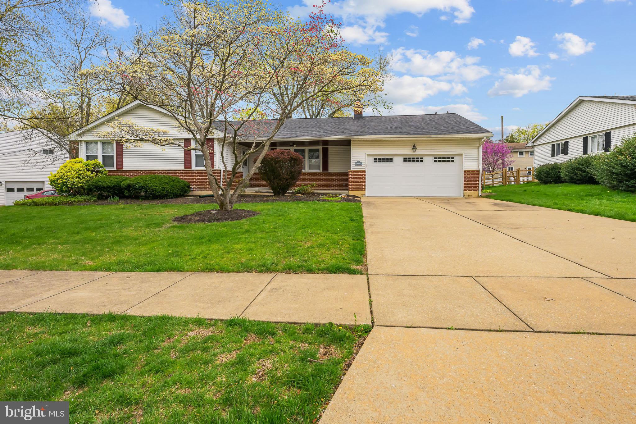 a front view of a house with a garden and trees