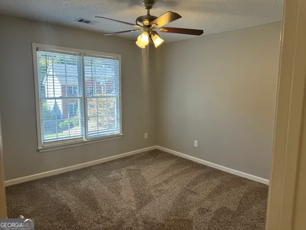 an empty room with windows and fan