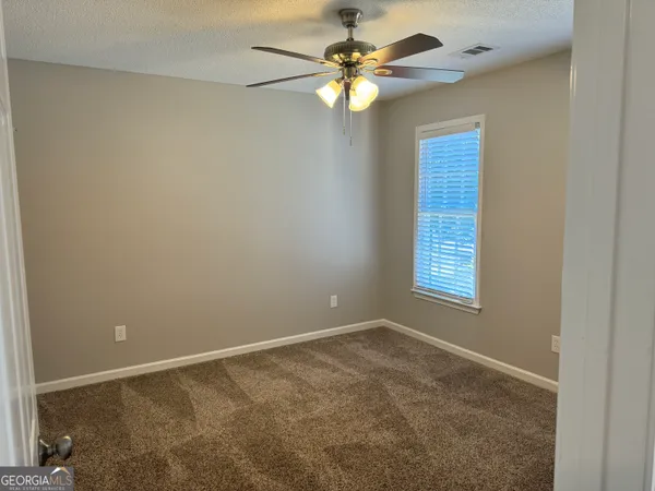 an empty room with windows and fan