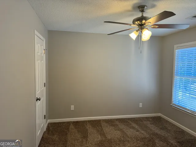 an empty room with windows and fan