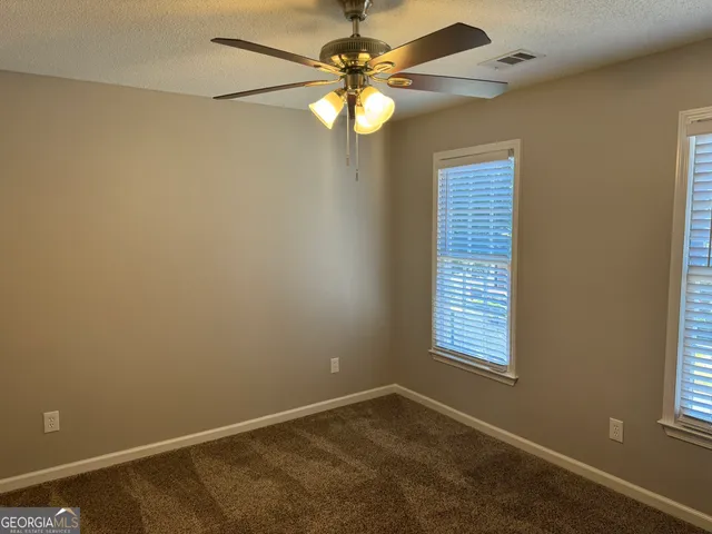 an empty room with windows and fan