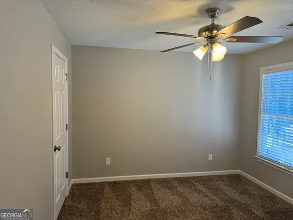 an empty room with windows and fan