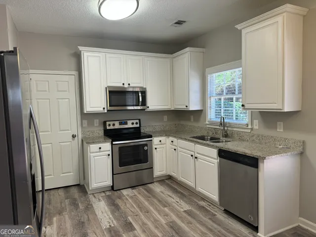 a kitchen with granite countertop a sink cabinets and stainless steel appliances