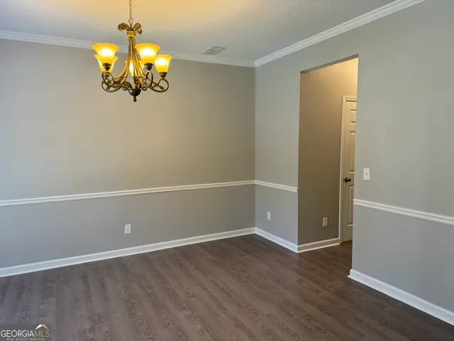 an empty room with wooden floor and chandelier