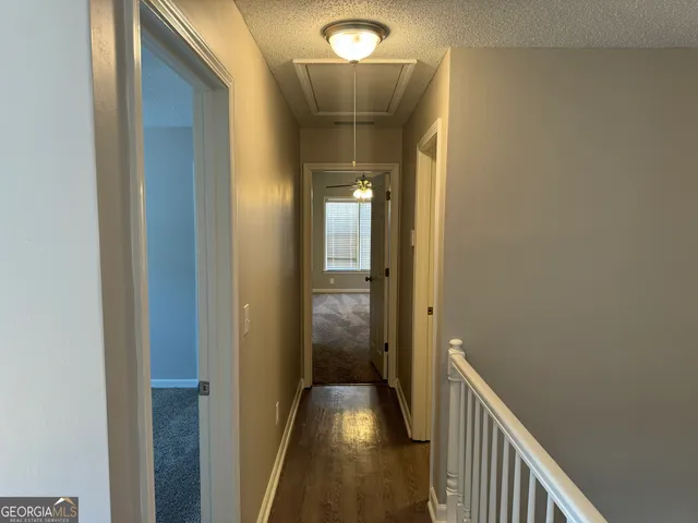 a view of a hallway view with wooden floor and a bathroom