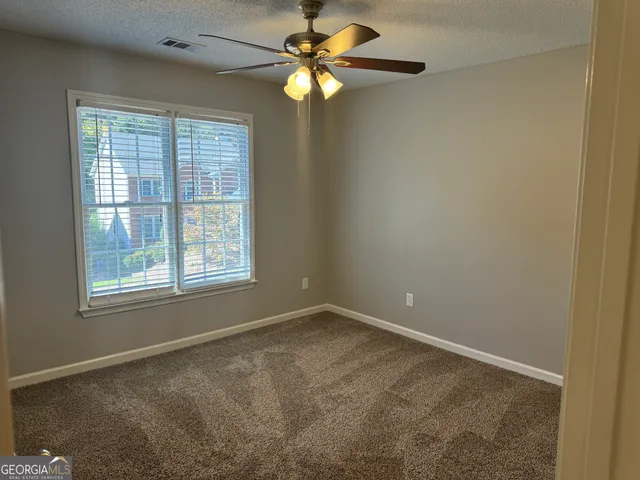 an empty room with windows and fan