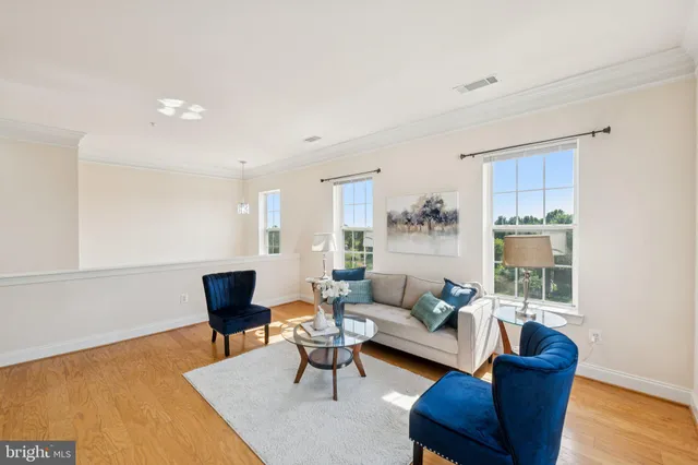 a living room with furniture kitchen view and a wooden floor