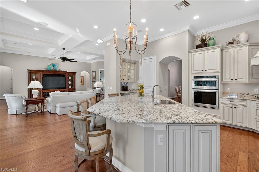 14495 Marsala Way Naples, FL 34109 - Photo 11 of 45 a kitchen with kitchen island granite countertop a stove a sink a oven a dining table and chairs