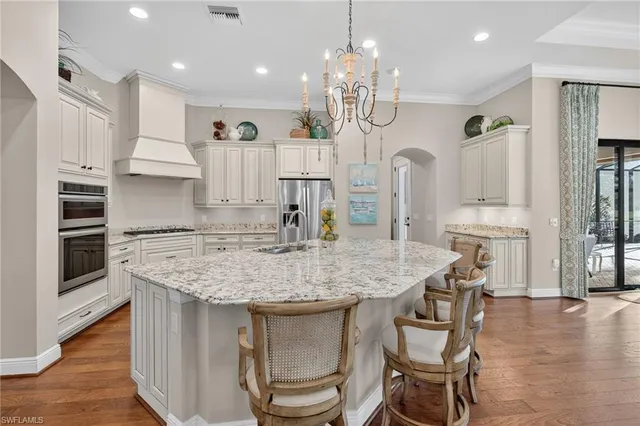 a kitchen with stainless steel appliances granite countertop a kitchen island a stove and a view of living room