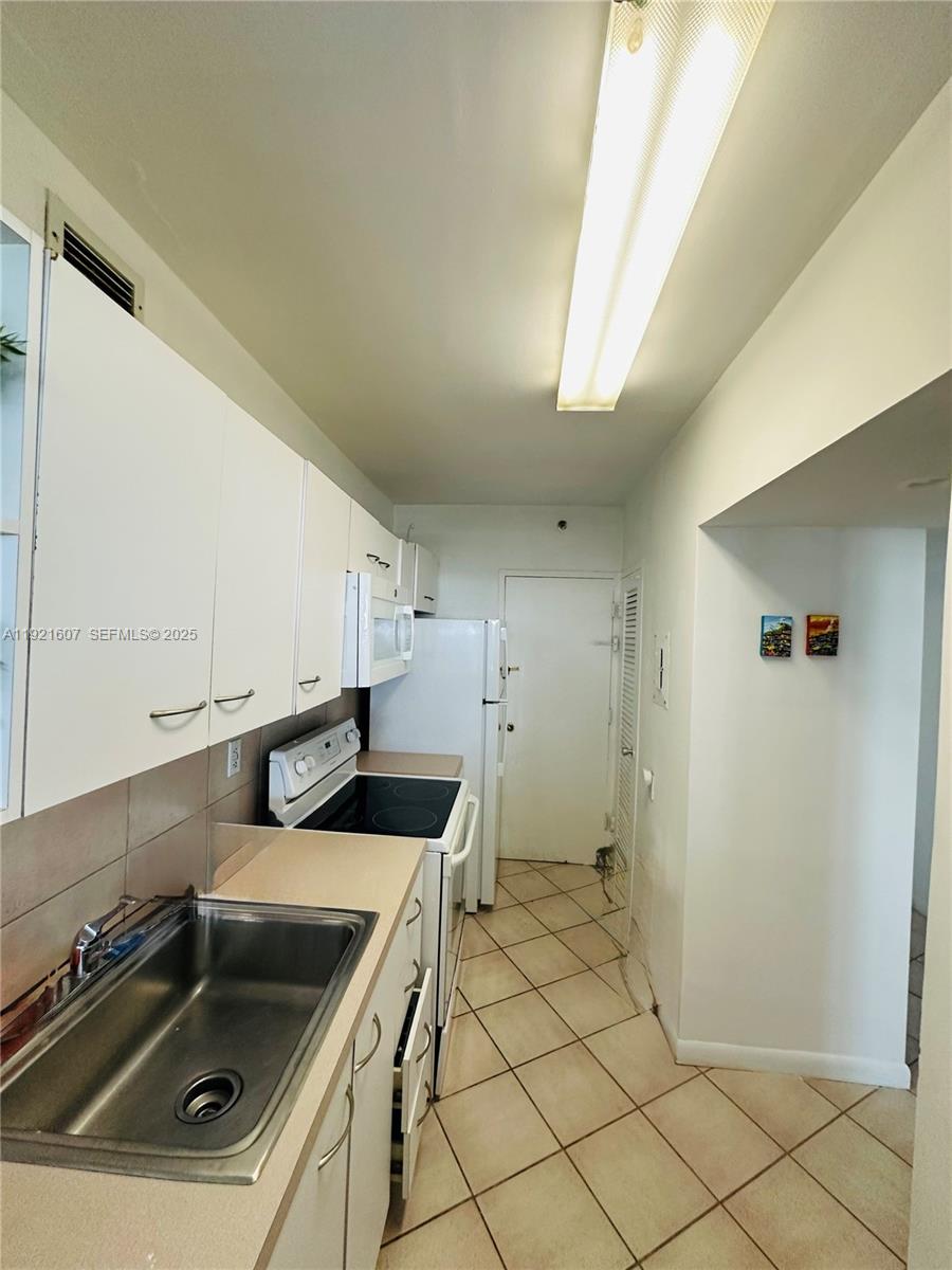 100 Lincoln Road, Unit 1427 Miami Beach, FL 33139 - Photo 19 of 32 a kitchen that has a sink and a stove