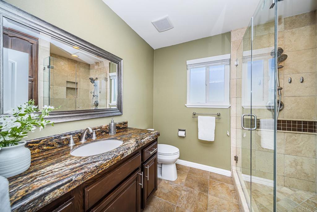 3801 Orange Way Oceanside, CA 92057 - Photo 36 of 52 a bathroom with a granite countertop sink a toilet a mirror and shower