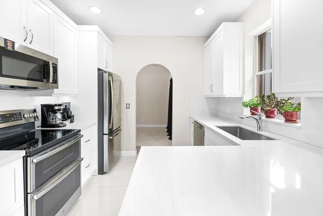 a kitchen with stainless steel appliances kitchen island granite countertop a refrigerator and a stove top oven