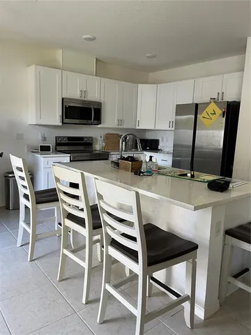 a kitchen with a stove a sink and white cabinets