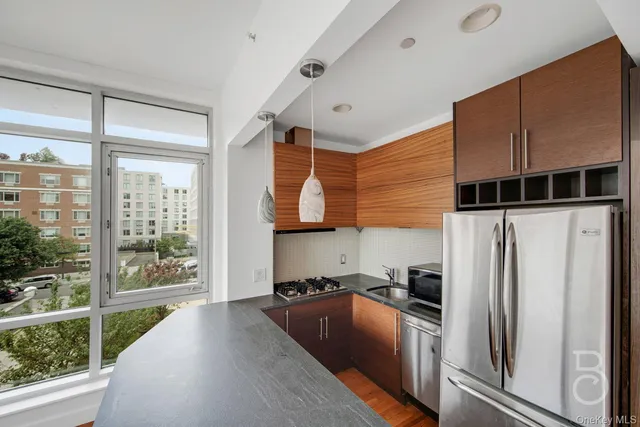 a kitchen with stainless steel appliances granite countertop a refrigerator a oven and white cabinets with wooden floors