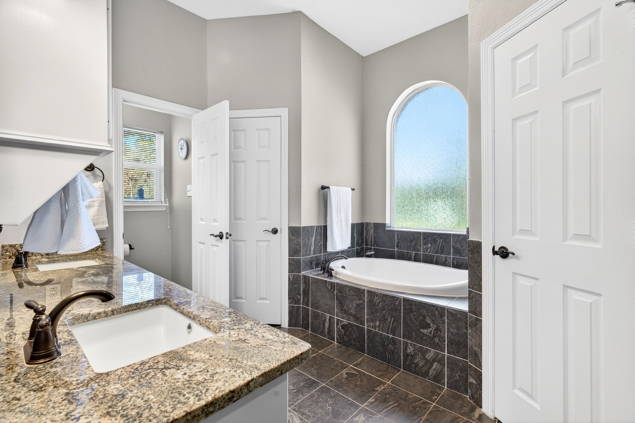 23620 Spring Branch Trail Montgomery, TX 77316 - Photo 15 of 27 A soaking tub with handheld wand sits beneath an arched window—paired with two walk-in closets for everyday ease.