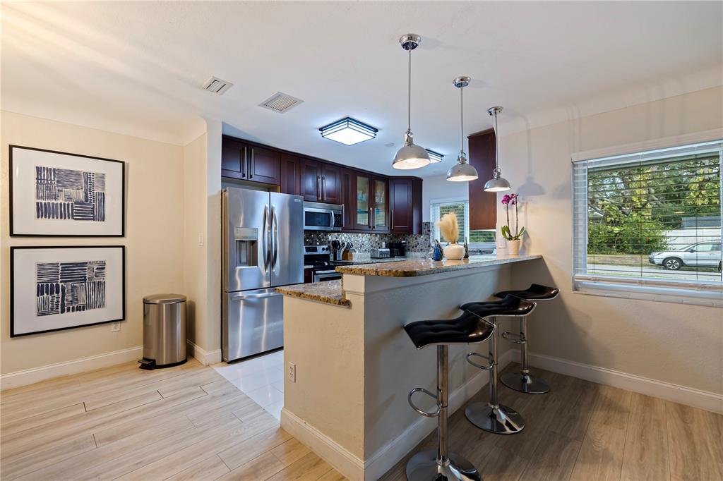 3282 Honeysuckle Road Largo, FL 33770 - Photo 14 of 44 a kitchen with stainless steel appliances granite countertop a refrigerator a sink dishwasher a stove and a dining table with wooden floor