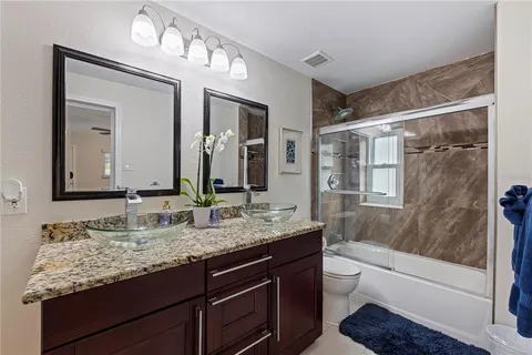 a bathroom with a granite countertop sink vanity mirror bathtub shower and a mirror