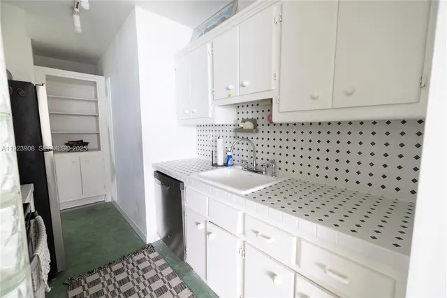a kitchen with granite countertop a sink a stove a refrigerator and cabinets
