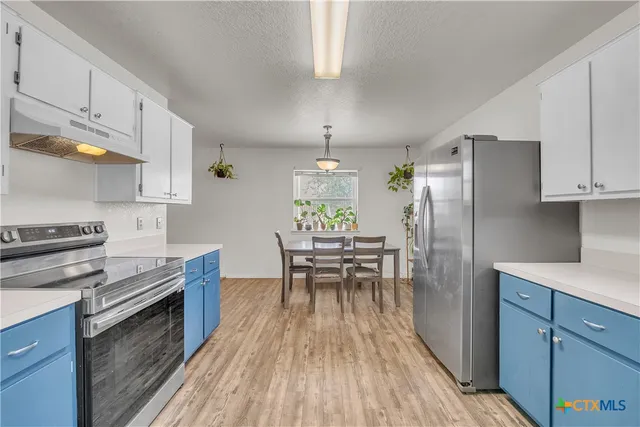 a kitchen with kitchen island wooden floors appliances and dining table