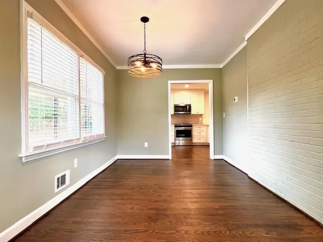 a view of empty room with wooden floor and window