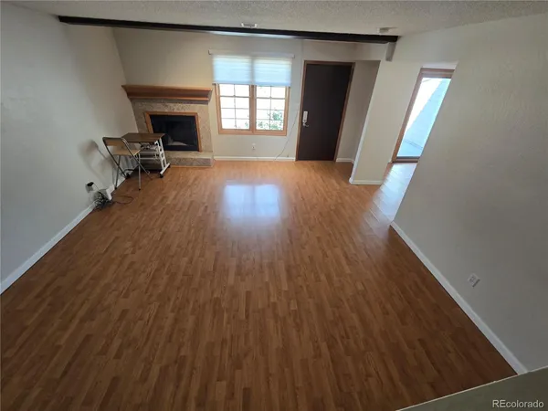 a view of empty room with wooden floor and fireplace