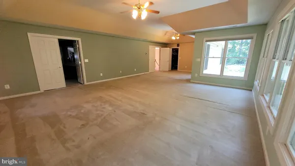 a view of an empty room with window and a kitchen