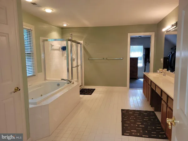 a bathroom with a tub a sink and a large mirror