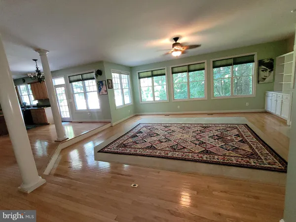 a view of empty room with wooden floor and fan