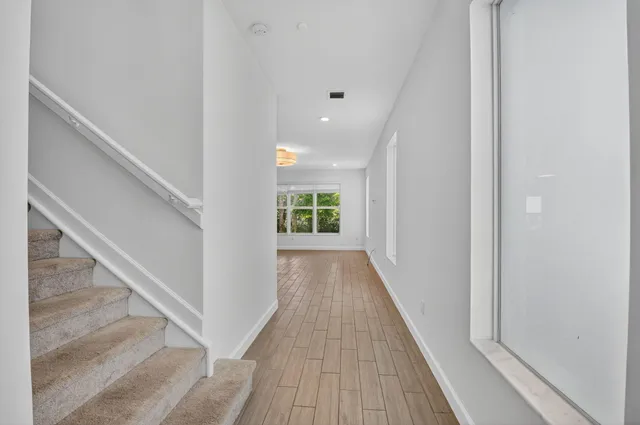 a view of a hallway with wooden floor and staircase