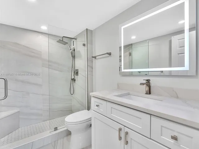a bathroom with a granite countertop sink toilet and shower