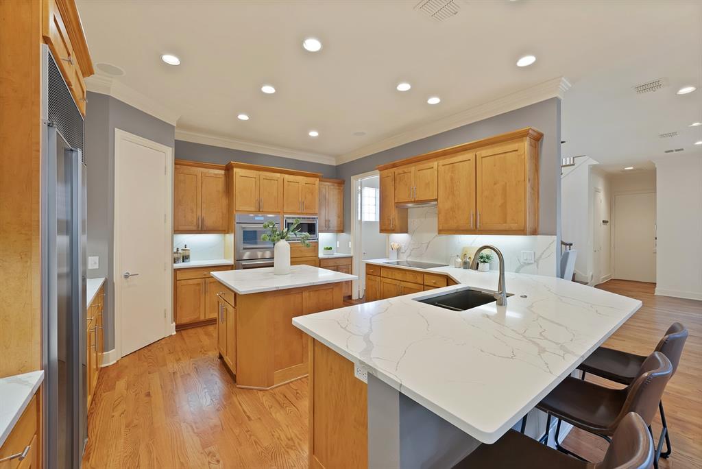 4010 Rawlins Street Dallas, TX 75219 - Photo 12 of 40 Kitchen with a peninsula, a kitchen breakfast bar, a center island, recessed lighting, and light wood-style floors