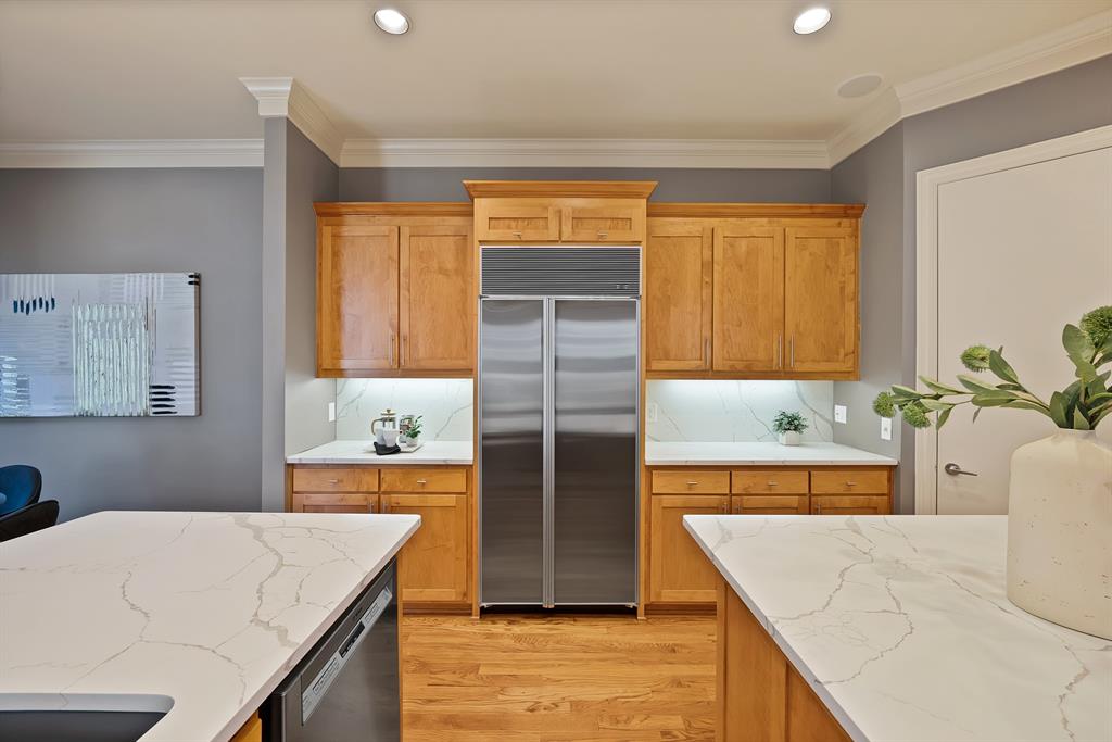 4010 Rawlins Street Dallas, TX 75219 - Photo 14 of 40 Kitchen with light stone counters, stainless steel appliances, light wood finished floors, crown molding, and wood finish cabinetry