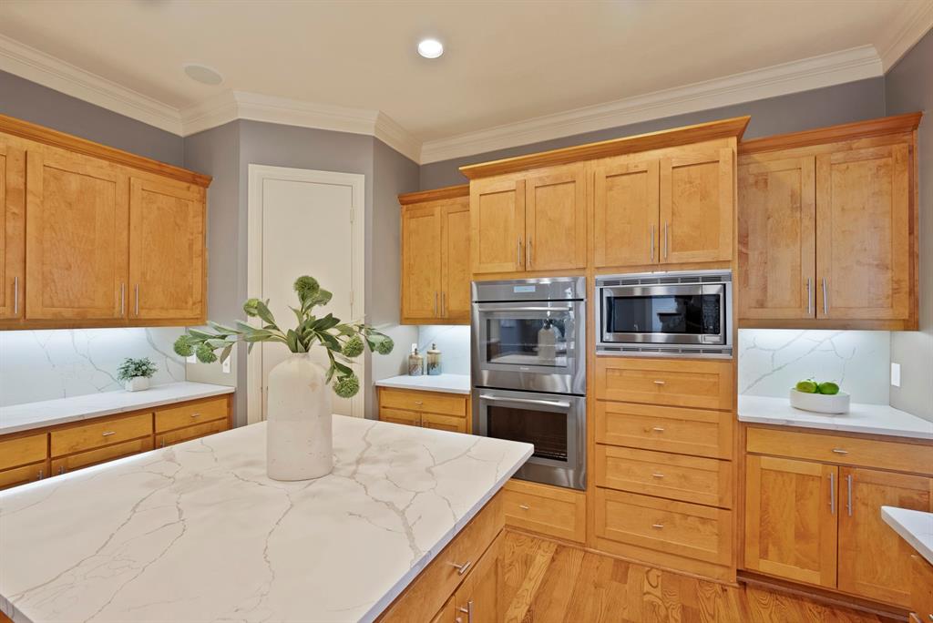 4010 Rawlins Street Dallas, TX 75219 - Photo 15 of 40 Kitchen with tasteful backsplash, stainless steel appliances, crown molding, light wood-style flooring, and light stone countertops