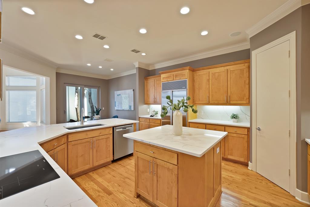 4010 Rawlins Street Dallas, TX 75219 - Photo 16 of 40 Kitchen with a center island, stainless steel appliances, recessed lighting, crown molding, and light wood-style flooring