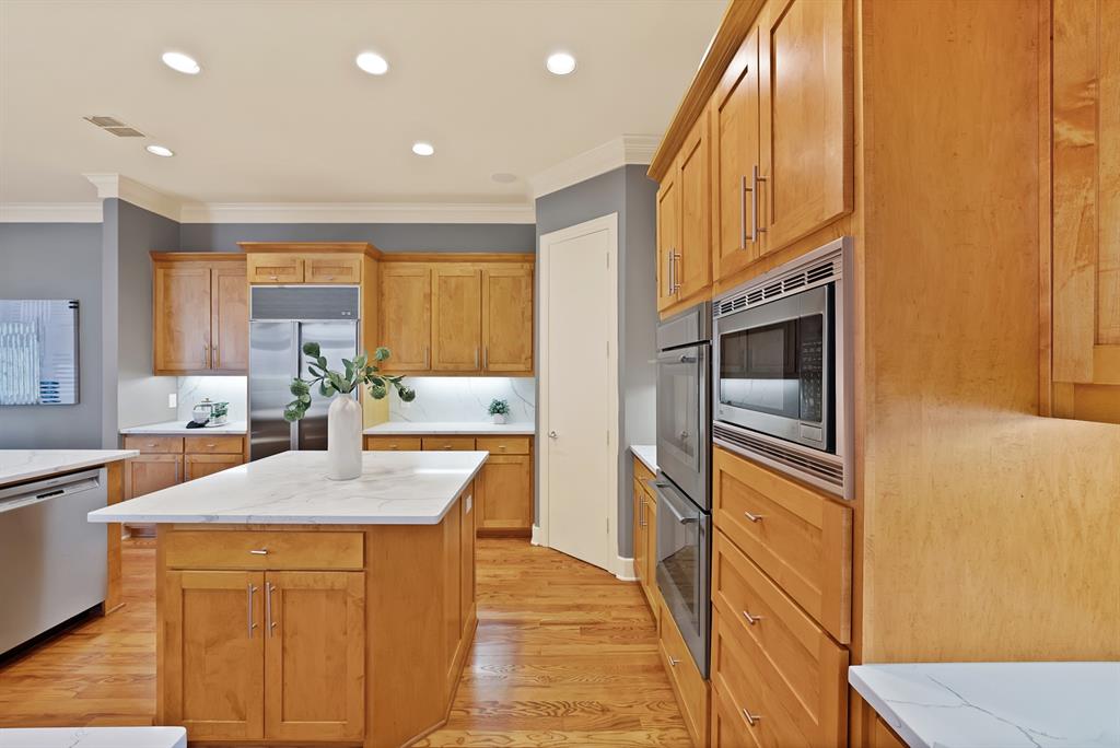 4010 Rawlins Street Dallas, TX 75219 - Photo 17 of 40 Kitchen featuring built in appliances, light wood-style flooring, recessed lighting, ornamental molding, and a center island