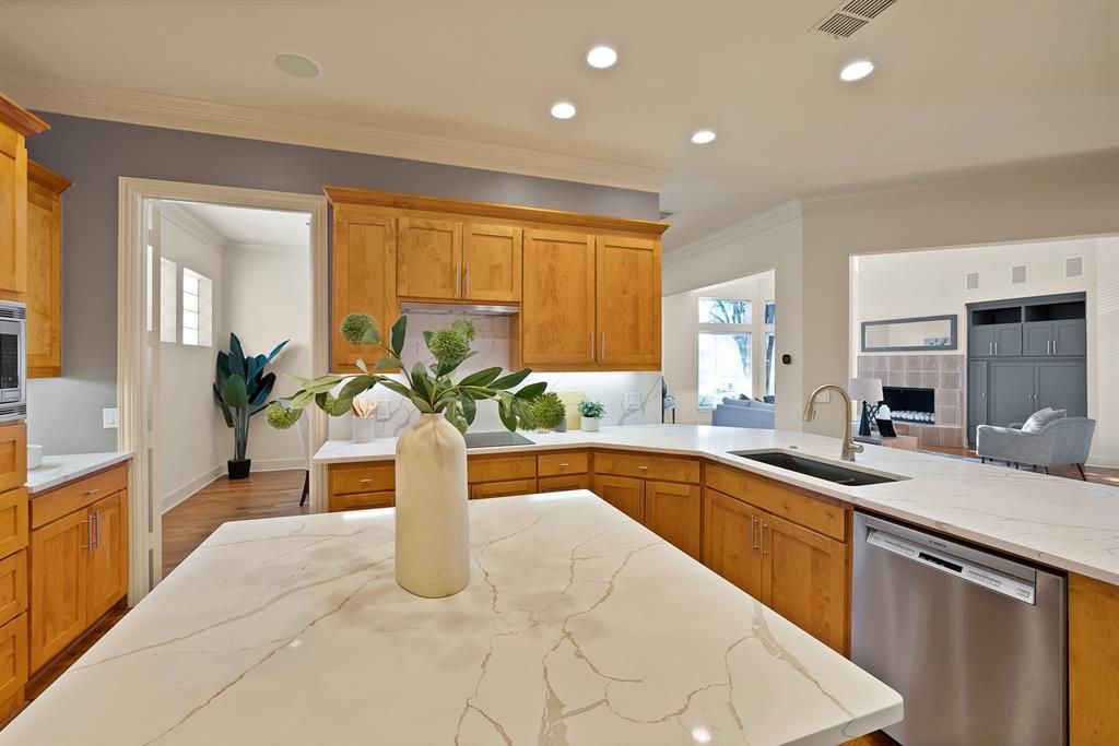 4010 Rawlins Street Dallas, TX 75219 - Photo 18 of 40 Kitchen featuring stainless steel appliances, ornamental molding, light stone countertops, wood finished floors, and wood finish cabinets