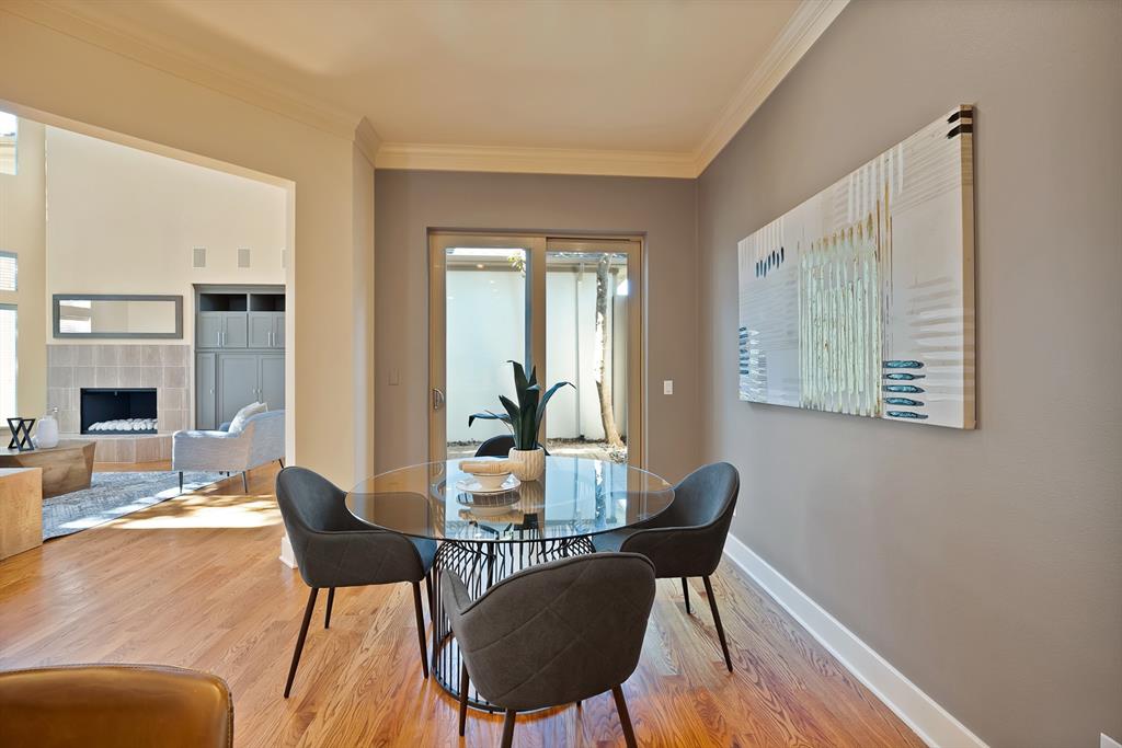 4010 Rawlins Street Dallas, TX 75219 - Photo 20 of 40 Dining area featuring a tiled fireplace, ornamental molding, and wood finished floors