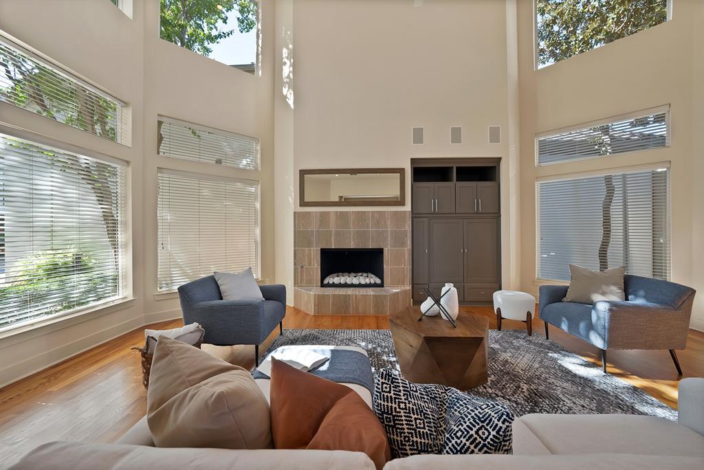 4010 Rawlins Street Dallas, TX 75219 - Photo 22 of 40 Living area with a tile fireplace, wood finished floors, a high ceiling, and healthy amount of natural light