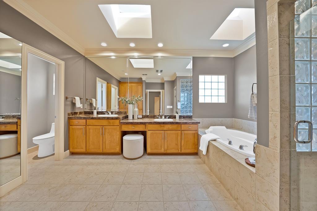4010 Rawlins Street Dallas, TX 75219 - Photo 32 of 40 Full bathroom with a skylight, double vanity, a shower stall, a garden tub, and crown molding