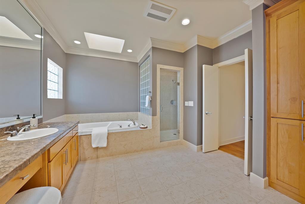 4010 Rawlins Street Dallas, TX 75219 - Photo 33 of 40 Full bathroom featuring a garden tub, a shower stall, vanity, crown molding, and a skylight