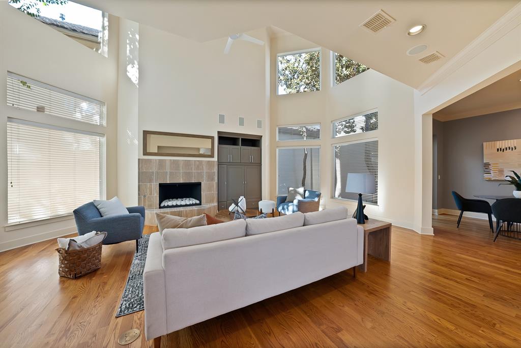 4010 Rawlins Street Dallas, TX 75219 - Photo 4 of 40 Living room with a tiled fireplace, crown molding, light wood-type flooring, a high ceiling, and recessed lighting