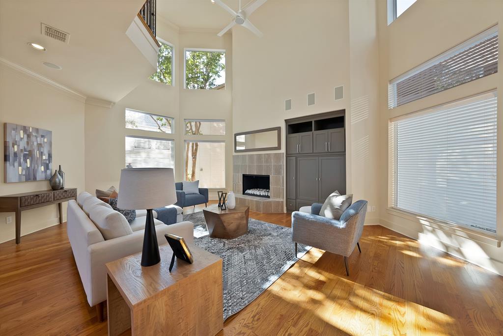 4010 Rawlins Street Dallas, TX 75219 - Photo 5 of 40 Living room featuring a tiled fireplace, wood finished floors, crown molding, ceiling fan, and a high ceiling
