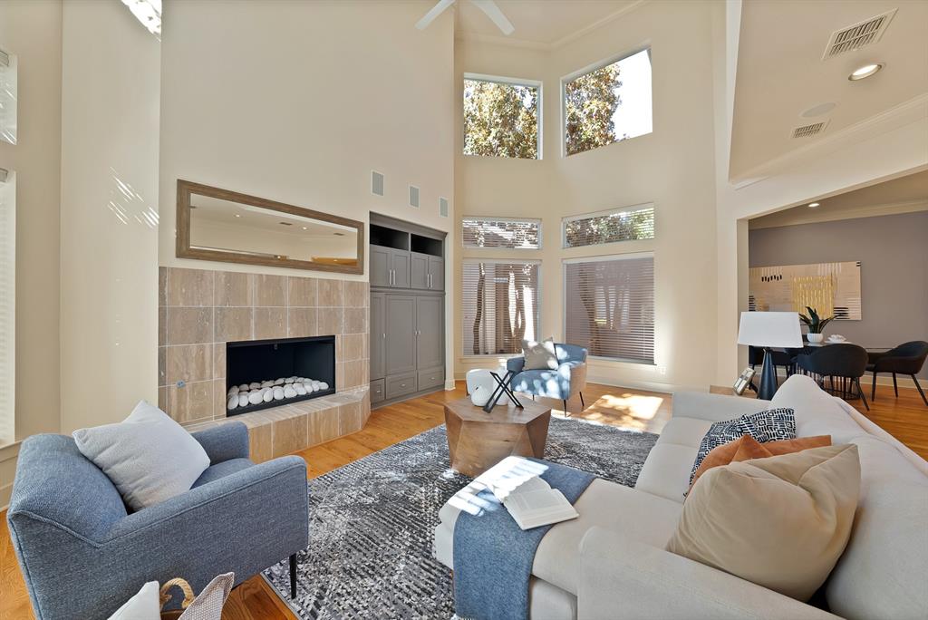 4010 Rawlins Street Dallas, TX 75219 - Photo 8 of 40 Living room with wood finished floors, recessed lighting, a tile fireplace, a high ceiling, and ornamental molding