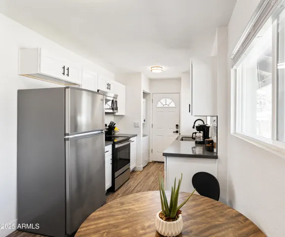 a kitchen with stainless steel appliances a refrigerator a sink a stove and white cabinets with wooden floor