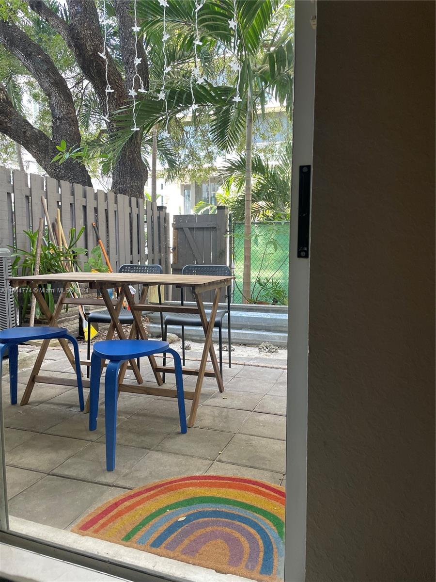 123 Southwest 17th Road, Unit 103 Miami, FL 33129 - Photo 5 of 21 a view of a patio with table and chairs with wooden floor and fence