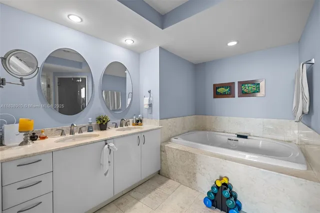 a bathroom with a tub double vanity sink and a mirror